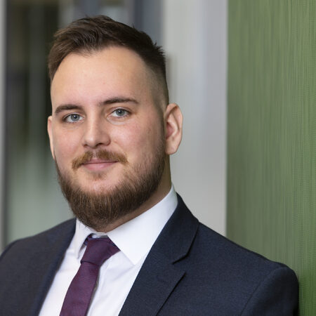 Man standing against a green wall, looking at camera.